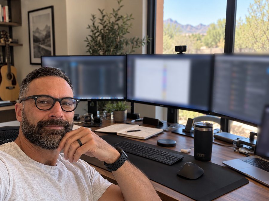 David at his desk with three monitors